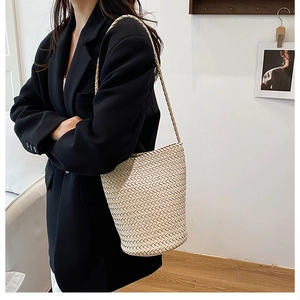 Detail of hand-woven cream bucket bag showing intricate texture and elegant shoulder strap