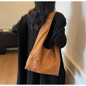 Detailed view of brown suede tote bag with drawstring and wide shoulder strap on model