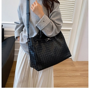 Detail of hand-woven black leather tote bag with adjustable shoulder strap and metal buckle