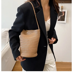 Detail of khaki hand-woven bucket bag styled with a minimalist black blazer outfit