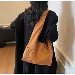 Detailansicht der karamellfarbenen Wildleder-Shopper-Tasche mit silbernen Ringen am Model