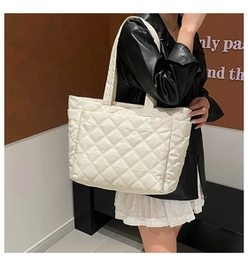 Detail of quilted rhombus tote bag in beige worn by model for daily commute style