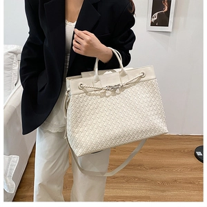 Detail of hand-woven cream white tote bag with dual handles and detachable shoulder strap