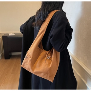 Detail of camel suede hobo bag showing large capacity, metallic ring, and textured finish