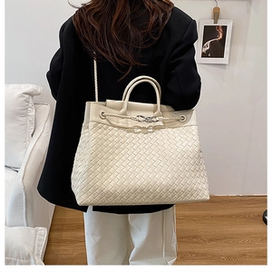 Detail of hand-woven cream leather tote bag with cylindrical handle and metal knot buckle
