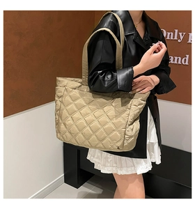 Close-up of beige quilted tote bag with large diamond stitching and long shoulder strap