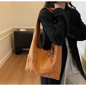 Close-up of brown suede hobo bag featuring metal ring detail and soft texture