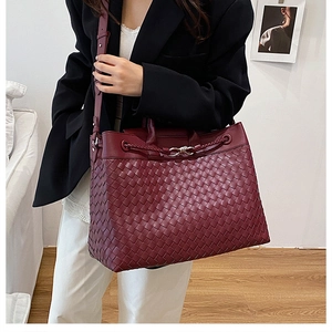 Detail of burgundy woven leather tote bag with silver knot buckle and shoulder strap