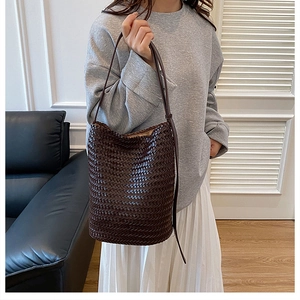 Detailed view of dark brown hand-woven leather bucket bag showing premium craftsmanship