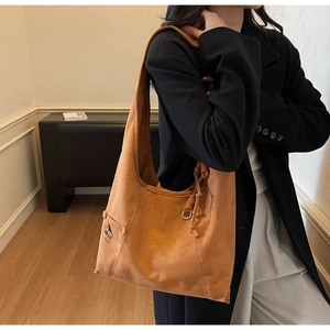 Close-up of brown suede hobo bag detailing fine stitching and decorative metal ring