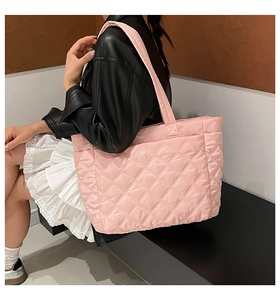 Detail of light pink quilted tote bag with padded texture and wide shoulder straps