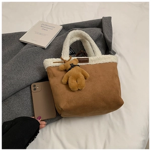 Detail of suede tote bag with white faux fur trim, fashion tag and cute bear charm