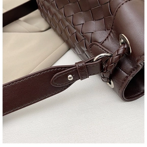Detail of dark brown hand-woven leather bag showing silver buckle and adjustable strap