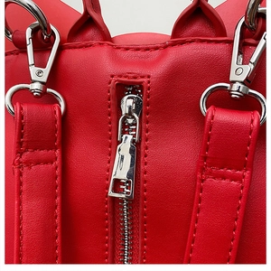 Macro detail of red leather gothic bat bag with silver metal zipper and stitching