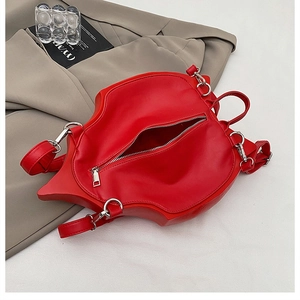 Detailed view of red lip-shaped handbag with glossy PU leather and silver metal zippers