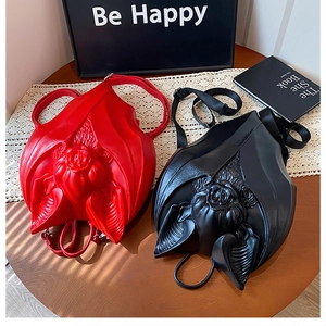 Detailed view of red and black gothic bat backpacks with 3D rose carved heads on a table