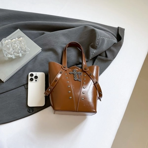 Brown leather punk bucket bag with metallic rivets and vintage cross charm detail