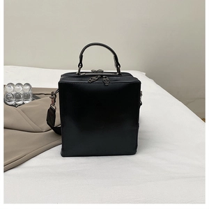 Detailed close-up of matte black square bag featuring unique metal skull zipper pulls