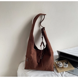 Macro detail of dark brown faux suede tote bag with metal buckles and drawstring