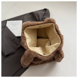 Detail of brown plush tote bag with magnetic snap closure and soft beige lining