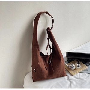 Close-up of a large dark brown suede tote bag with metal ring and shoulder strap