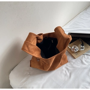 Detail of brown suede tote bag featuring a black fabric lining and functional zip pocket
