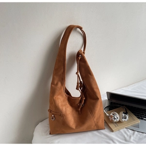 Detailed close-up of a brown suede hobo bag with drawstring and silver hardware accents