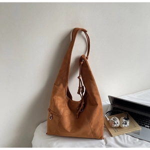 Detailed view of caramel suede hobo bag with drawstring and metal ring decor
