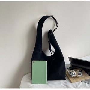 Detail of a large black suede hobo bag shown with a laptop for size scale and daily use