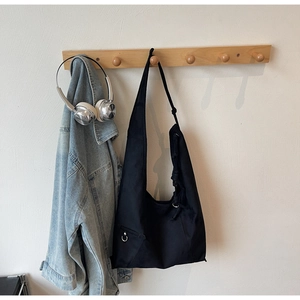 Detail of black suede tote bag featuring metallic ring ornament and knotted shoulder strap