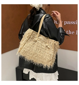 Détail du grand sac cabas beige à franges en raphia porté à l'épaule pour femme