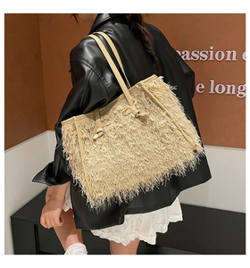 Détail d'un sac cabas tissé beige à franges porté avec une tenue moderne et bandoulière