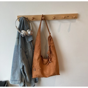 Detail of brown suede hobo bag with knotted shoulder strap and metal ring pocket on hanger