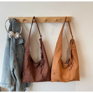 Close-up of suede hobo bags in brown and tan featuring knot details and metal rings