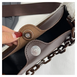Detailed shot of brown leather and faux shearling bag with magnetic buckle closure