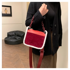 Detail of burgundy velvet crossbody bag with white faux fur trim and red chain strap