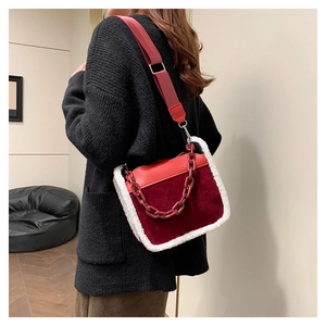 Detail of burgundy suede shoulder bag with white faux fur trim and resin chain strap