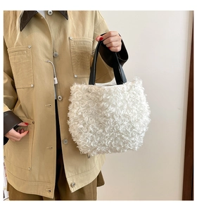 Close-up of fluffy white faux fur texture and black leather handles of the handbag
