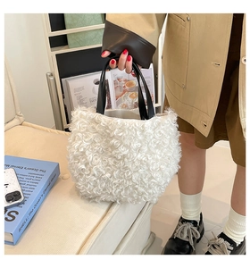 Close-up of plush white faux fur tote bag with black leather handles held by a model