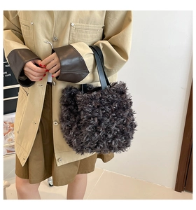 Deep grey curly faux fur tote bag with black leather handles shown in use by a model