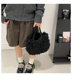 Detail shot of black curly faux shearling fabric and smooth tote bag handle texture