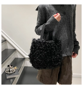 Close-up of black textured faux fur tote bag with smooth handles in a modern indoor setting