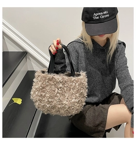 Detail of oatmeal lamb wool tote bag with black handles held by a model on stairs