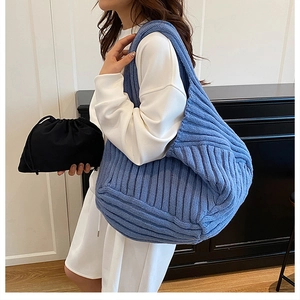 Detail of light blue knit tote bag showing textured weave and black drawstring inner pouch