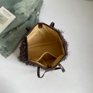 Grand cabas en peluche marron foncé avec doublure jaune et poignées en cuir sur fond blanc