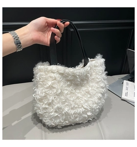 Detail of white faux shearling tote bag with premium black leather handles in hand