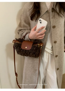 Nahaufnahme der braunen Lammfell-Tasche mit Lederklappe und goldenen Metalldetails