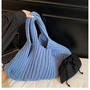 Detailed knit texture of blue striped hobo tote bag with black drawstring inner pouch