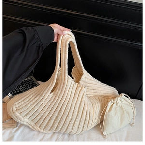 Close-up of cream knit tote bag and drawstring pouch with vertical stripe texture