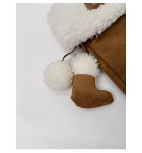 Close-up of a brown suede mini boot bag charm with white plush fur and fuzzy pompom detail